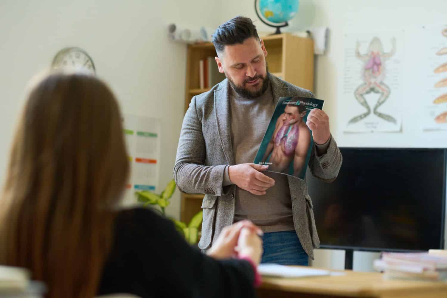 Teacher showing cover of anatomy book